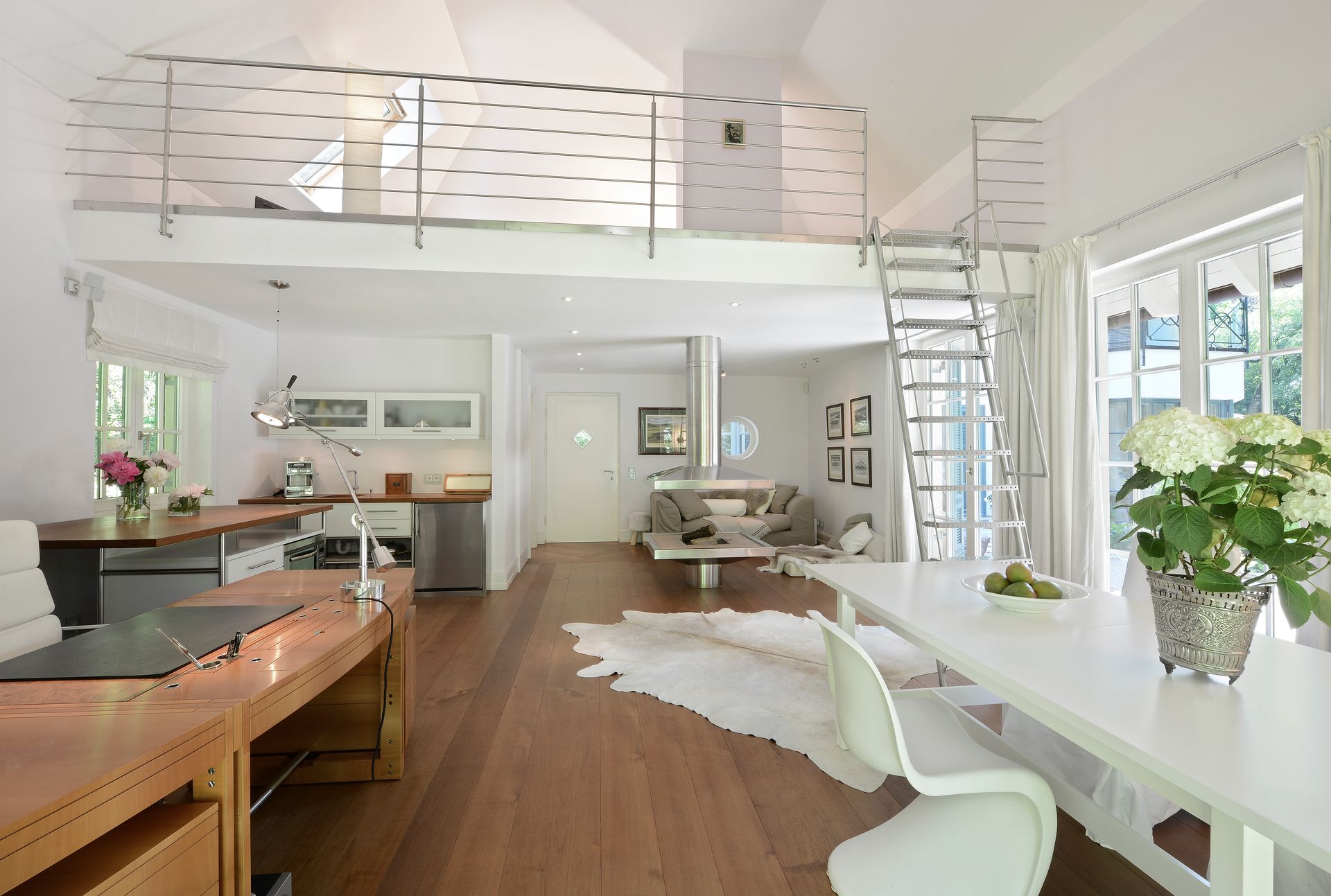 Bright, airy interior with loft, kitchen, dining area, and living space; white and wood tones.