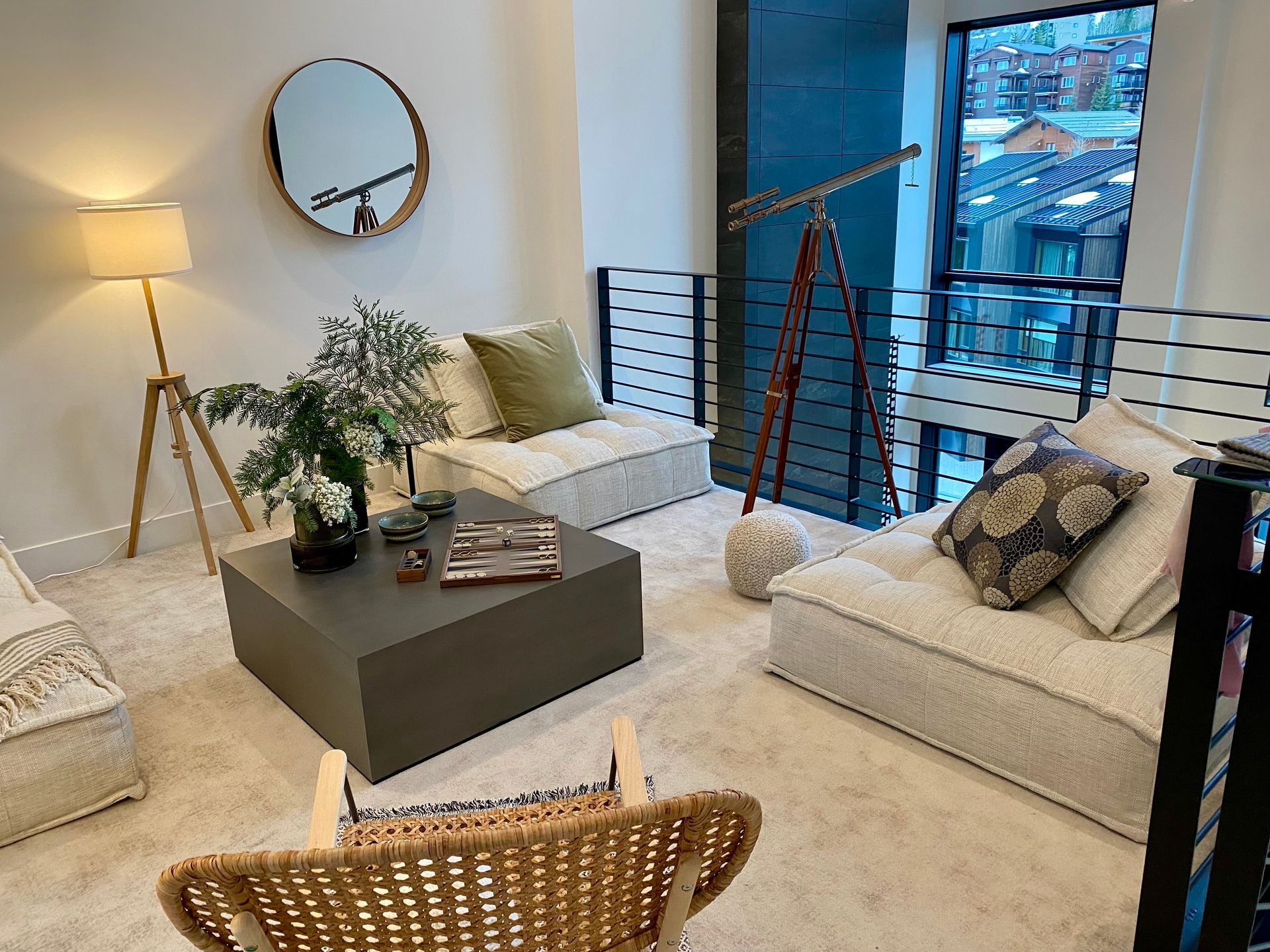 Living room with modern decor: neutral color palette, low seating, telescope, and a round mirror.