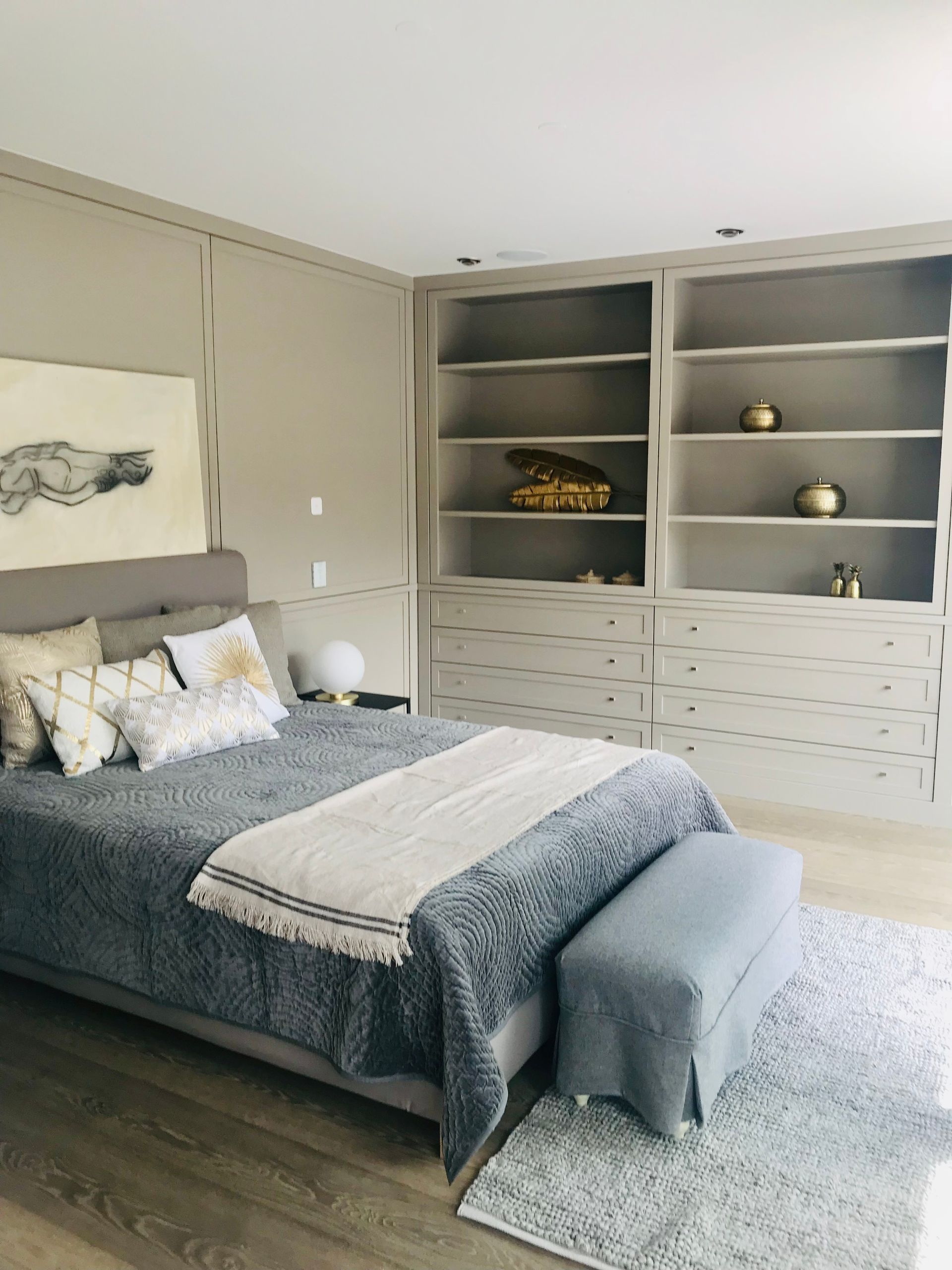 Bedroom with gray walls, bed, built-in shelving, and a patterned rug.