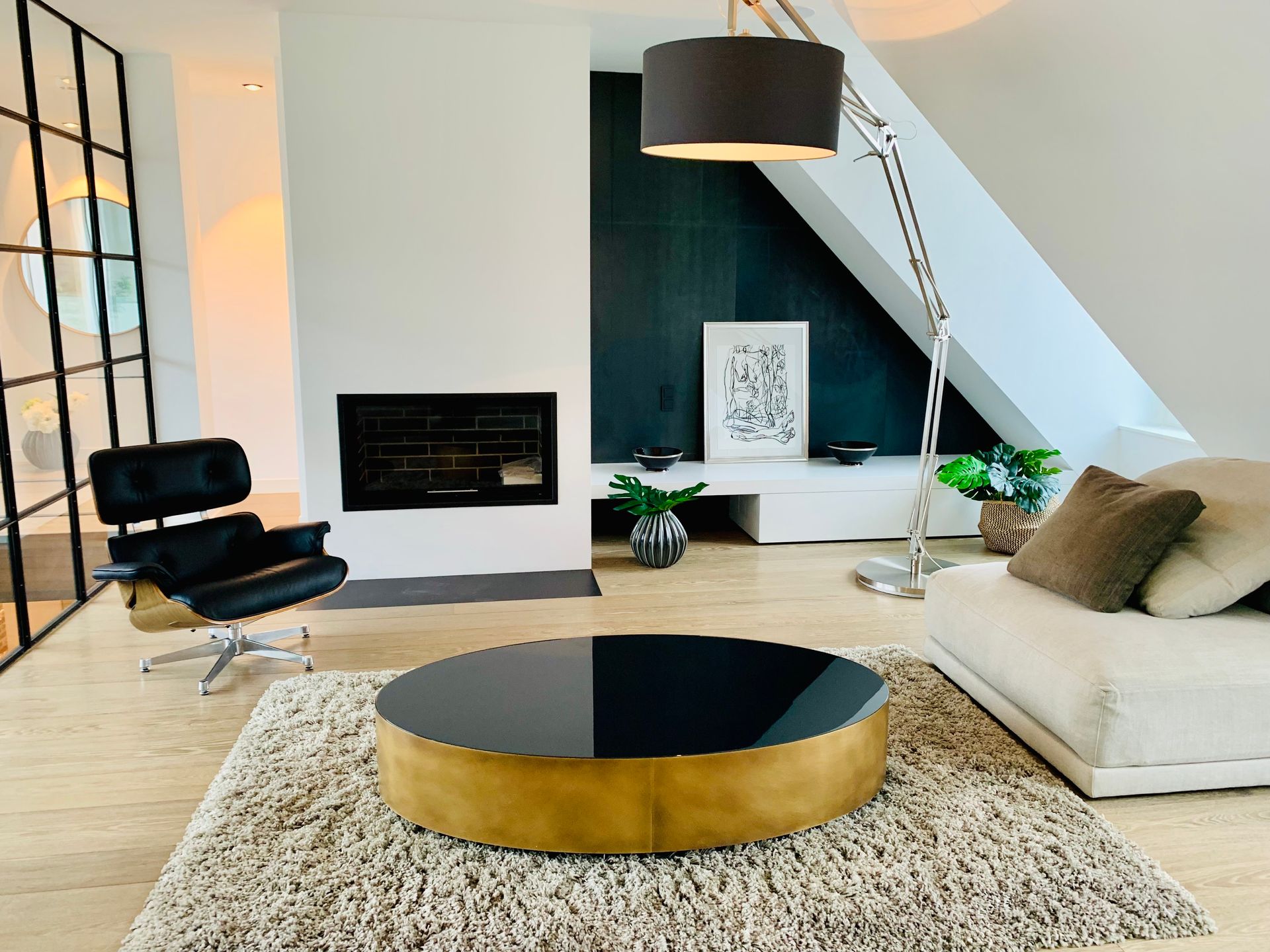 Modern living room with black chair, fireplace, and round coffee table on shag rug.
