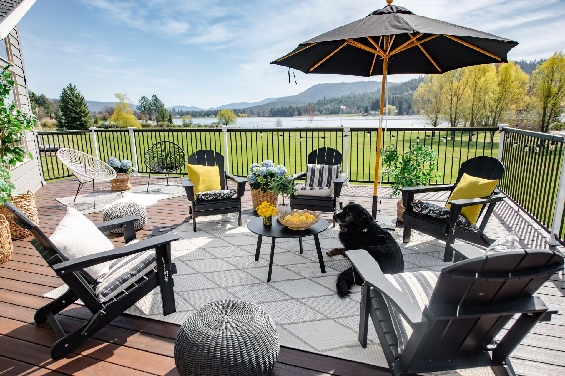 Outdoor patio with black wicker seating, umbrella, grill, and mountain view over a green valley