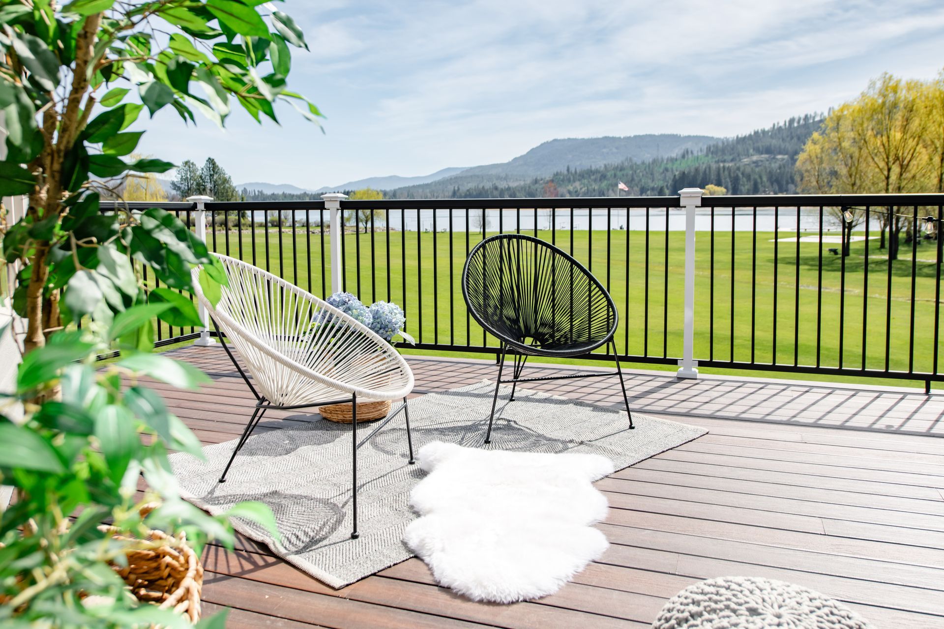 Patio with two chairs and a white rug overlooking a grassy field and distant hills