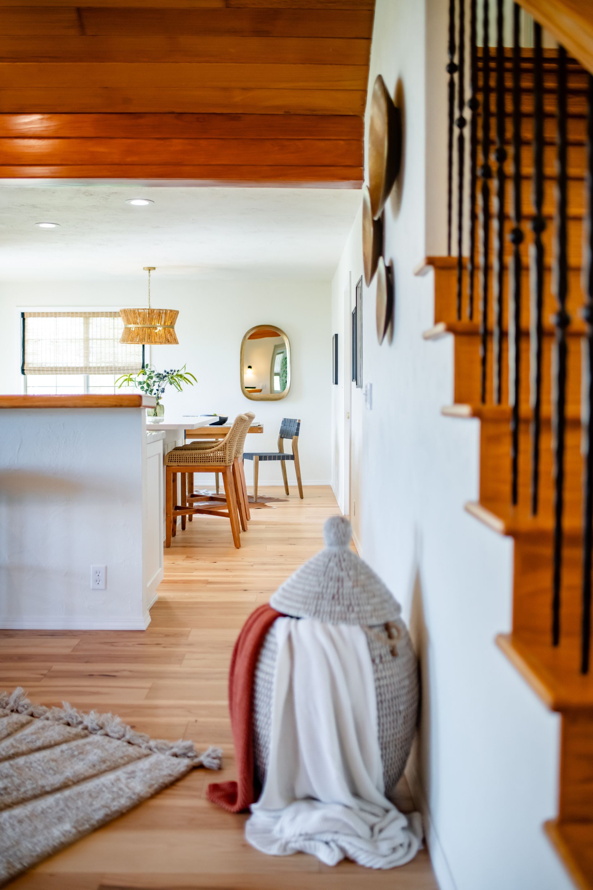 Bright, modern home hallway with wooden stairs, dining area, and a draped chair in the foreground