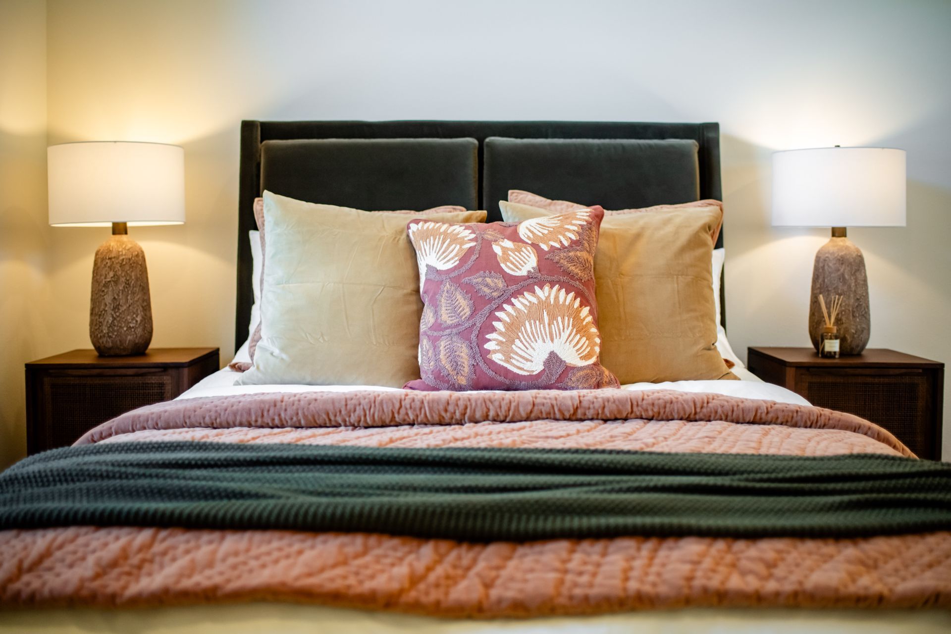 Neatly made bed with white pillows, patterned accent pillow, and bedside lamps in a cozy bedroom