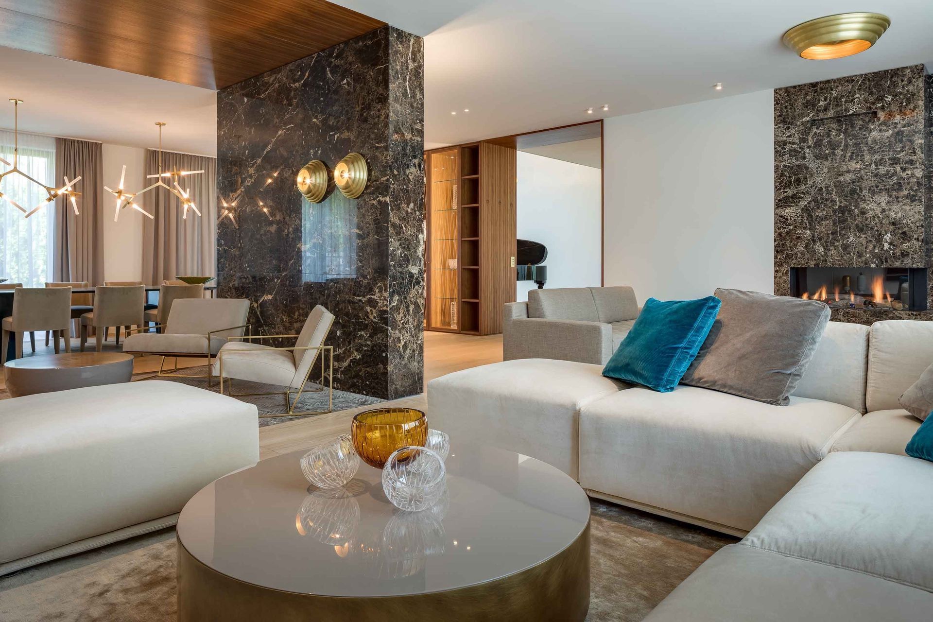 Modern living room with sectional sofa, marble accents, and fireplace.