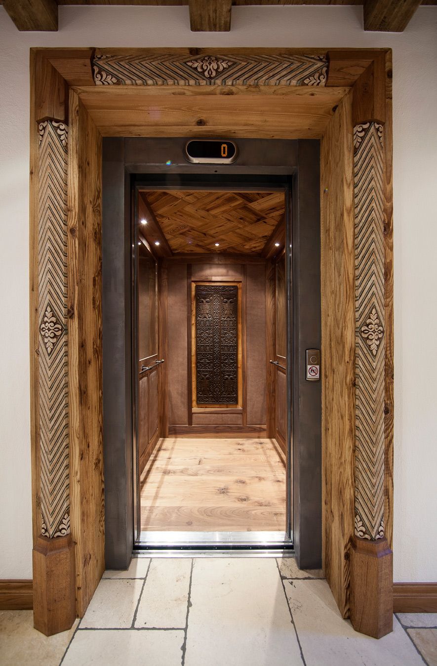 Wooden elevator with decorative trim and open doors.