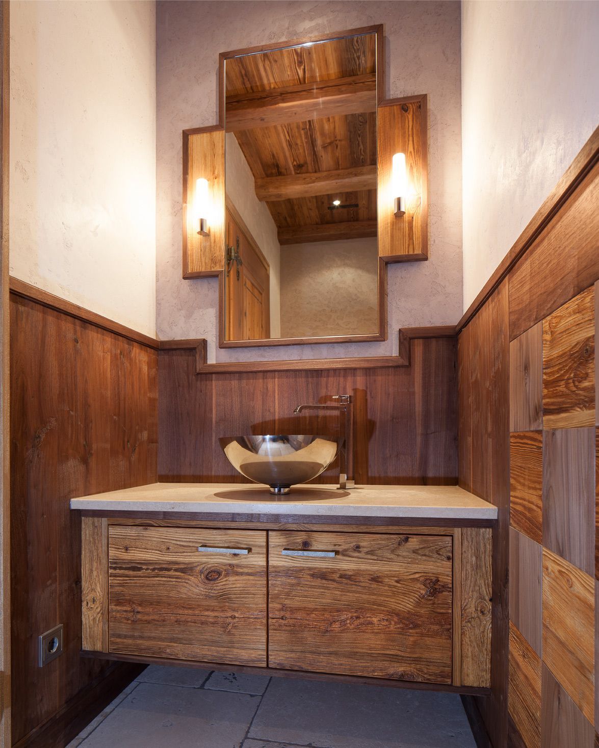 Rustic wooden bathroom with floating vanity, mirror, and sconces.