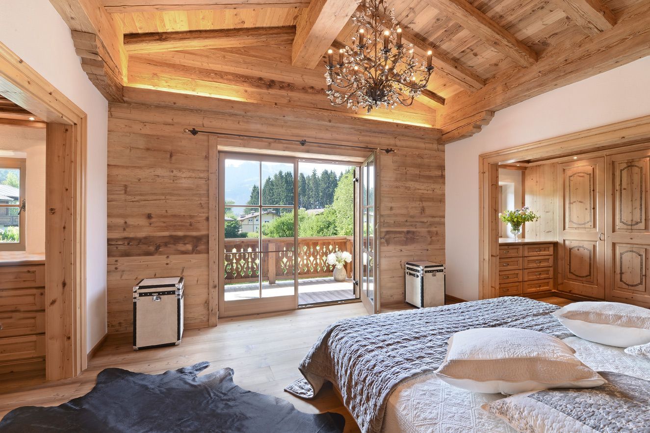 Wooden bedroom with balcony, bed, chandelier, and air purifiers.