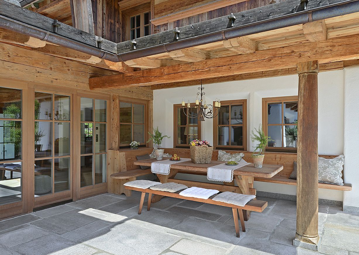 Outdoor wooden dining set on a stone patio, under a wooden roof.