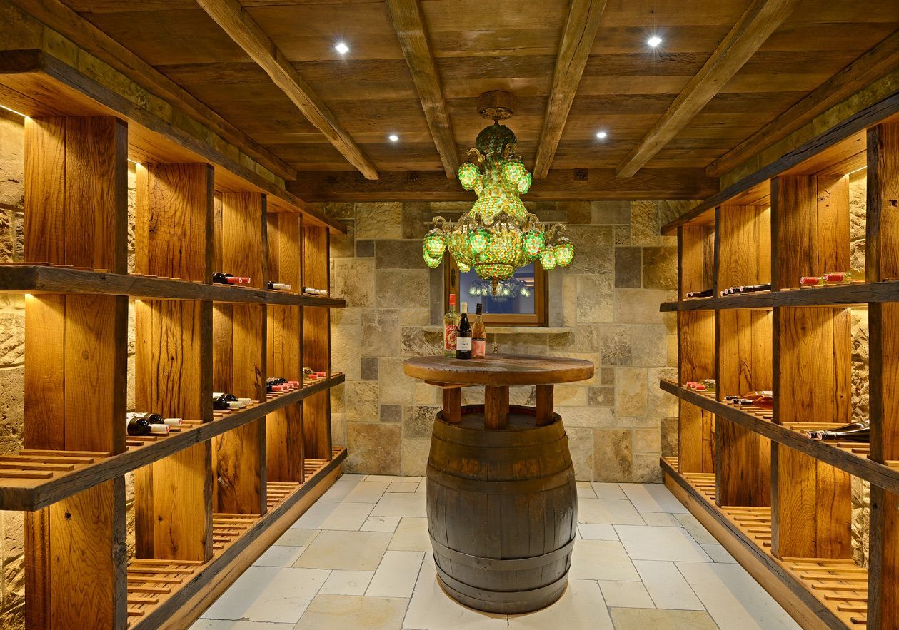 Wine cellar with wooden racks, stone walls, and a barrel table.
