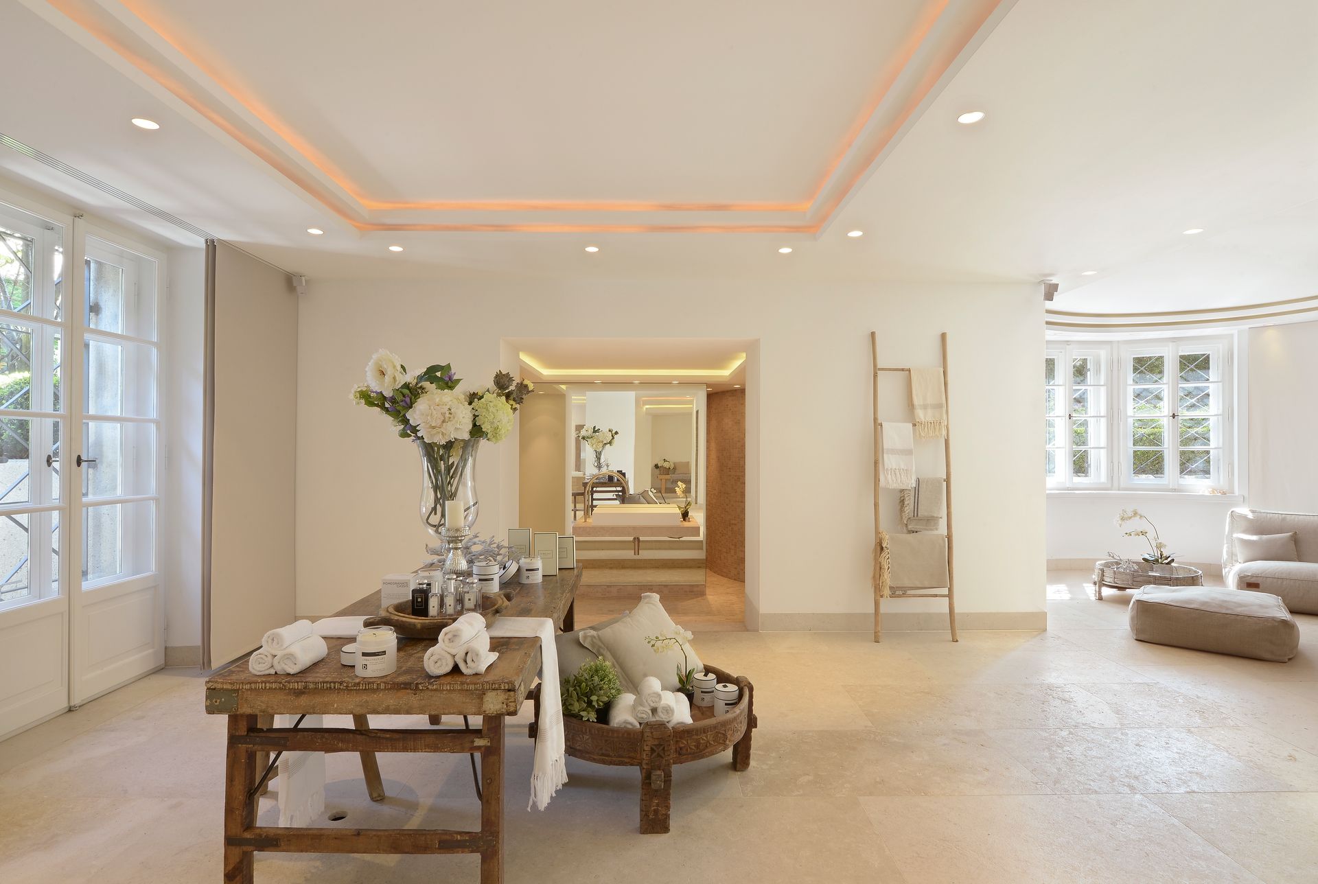 Bright, airy interior with natural light, featuring a rustic table, open doorway, and neutral-toned furniture.