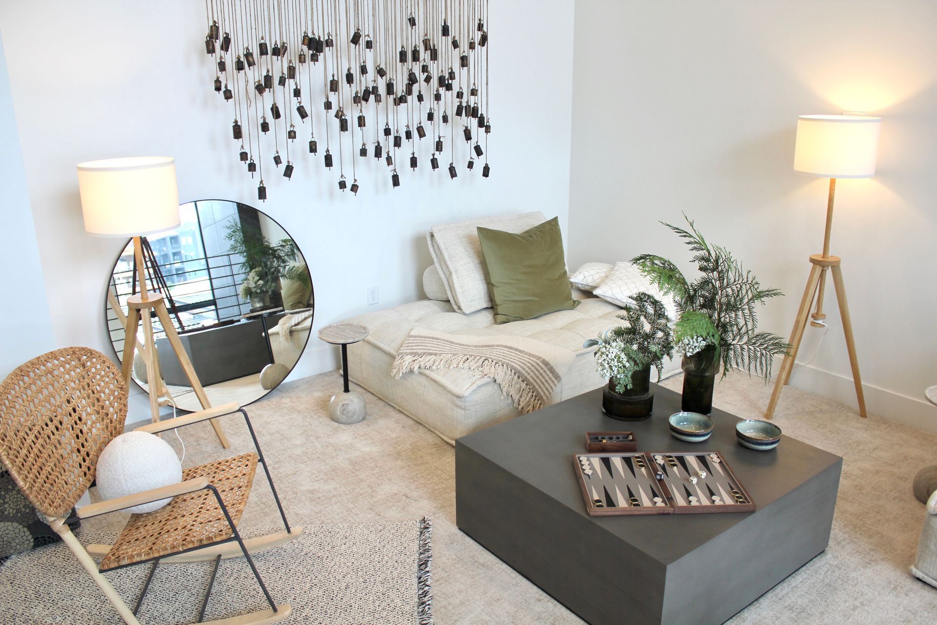 Cozy living room with beige rug, a low gray coffee table, round mirror, and two wooden lamps.