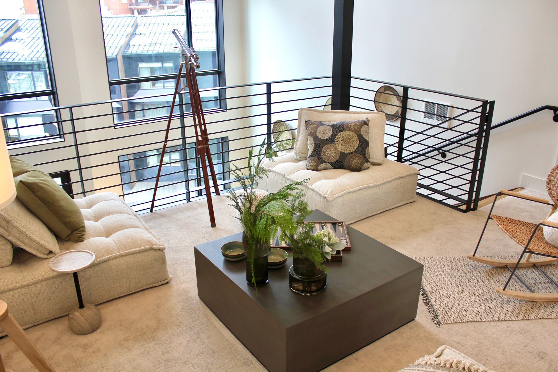 Living room with two-level seating area, coffee table, and metal railing.