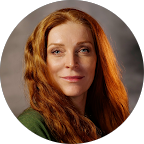 Portrait of a red-haired woman with a slight smile against a soft gray background
