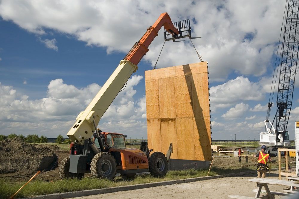 A Forklift Is Lifting A Large Piece Of Wood On A Construction Site — S & W Crane Hire In Whitsundays, QLD