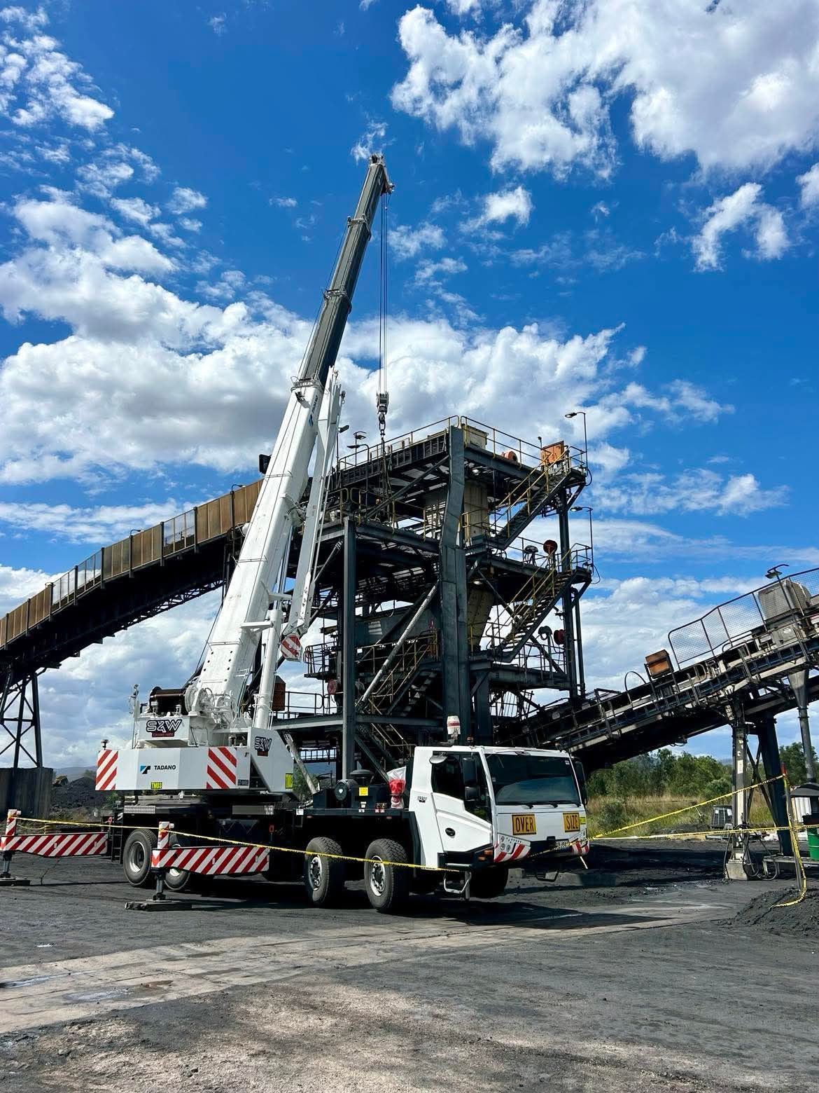 A large crane is sitting on top of a truck in front of a building — S & W Crane Hire In Bowen, QLD