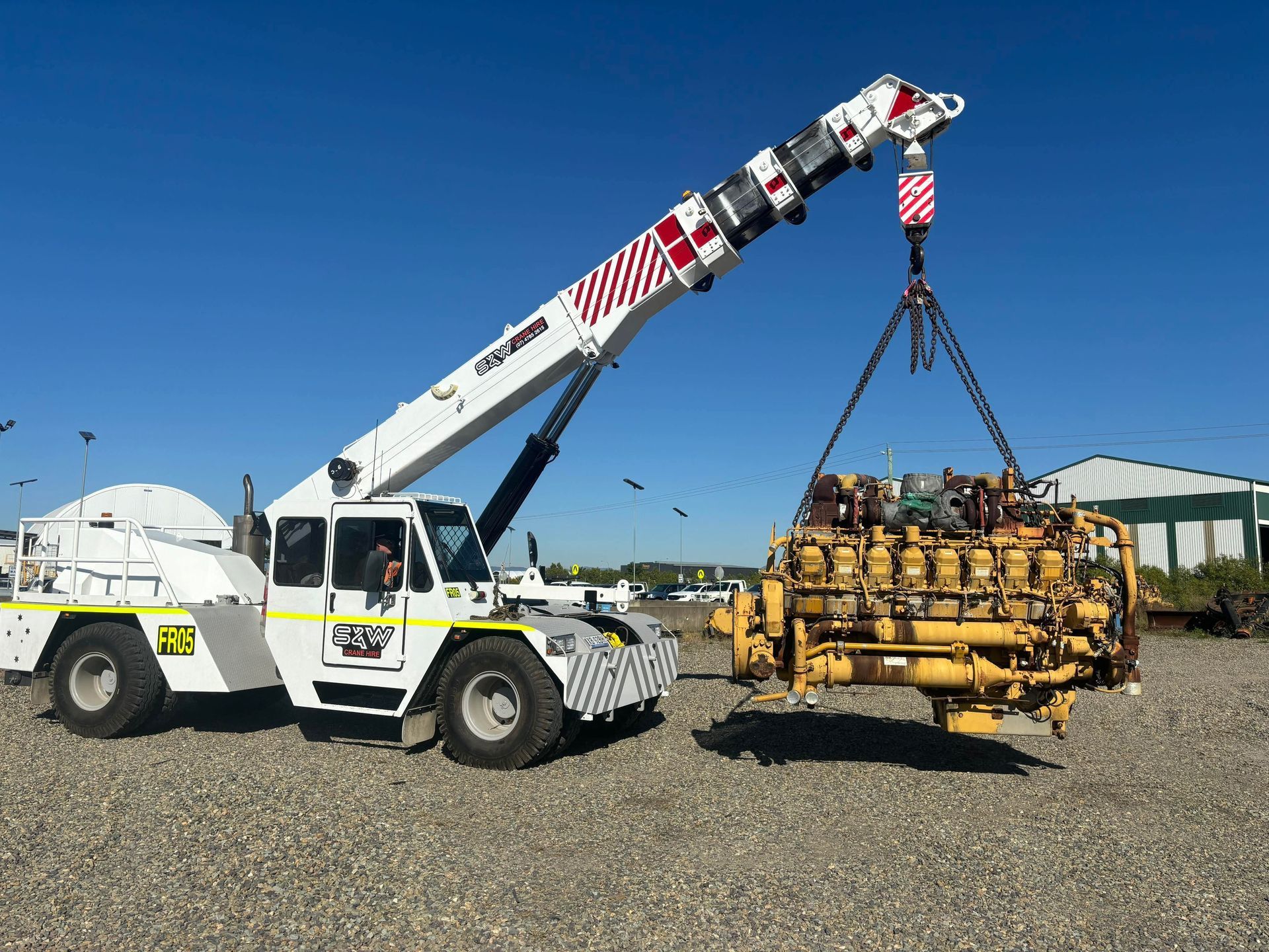 A crane is lifting a large engine out of a truck - S & W Crane Hire In Bowen, QLD