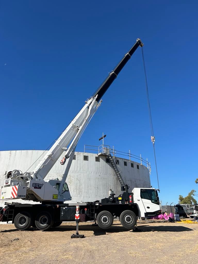 A large crane is sitting on top of a truck in a parking lot — S & W Crane Hire In Collinsville, QLD
