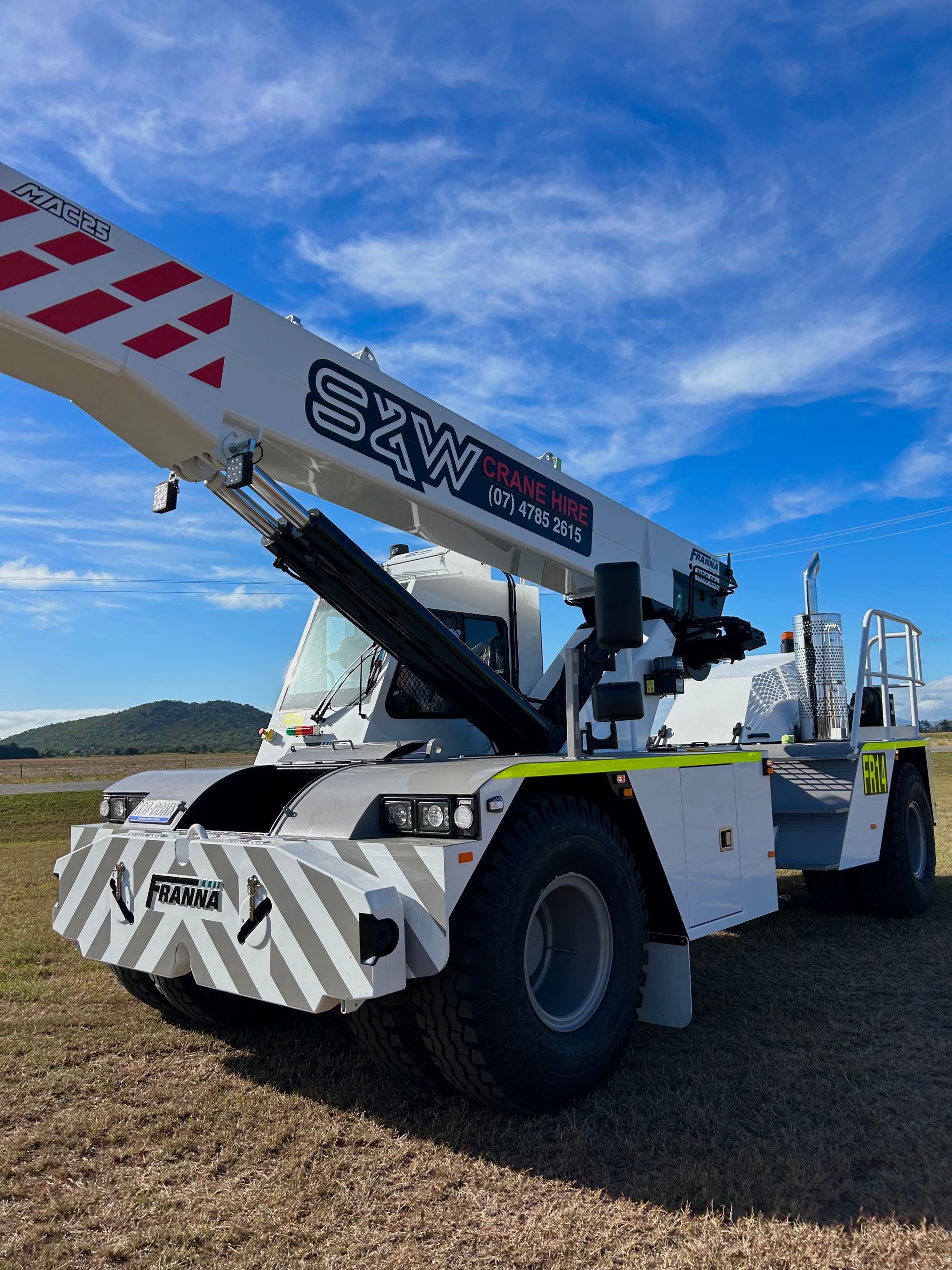 A Crane Is Parked On A Field Of Grass — S & W Crane Hire In Bowen, QLD