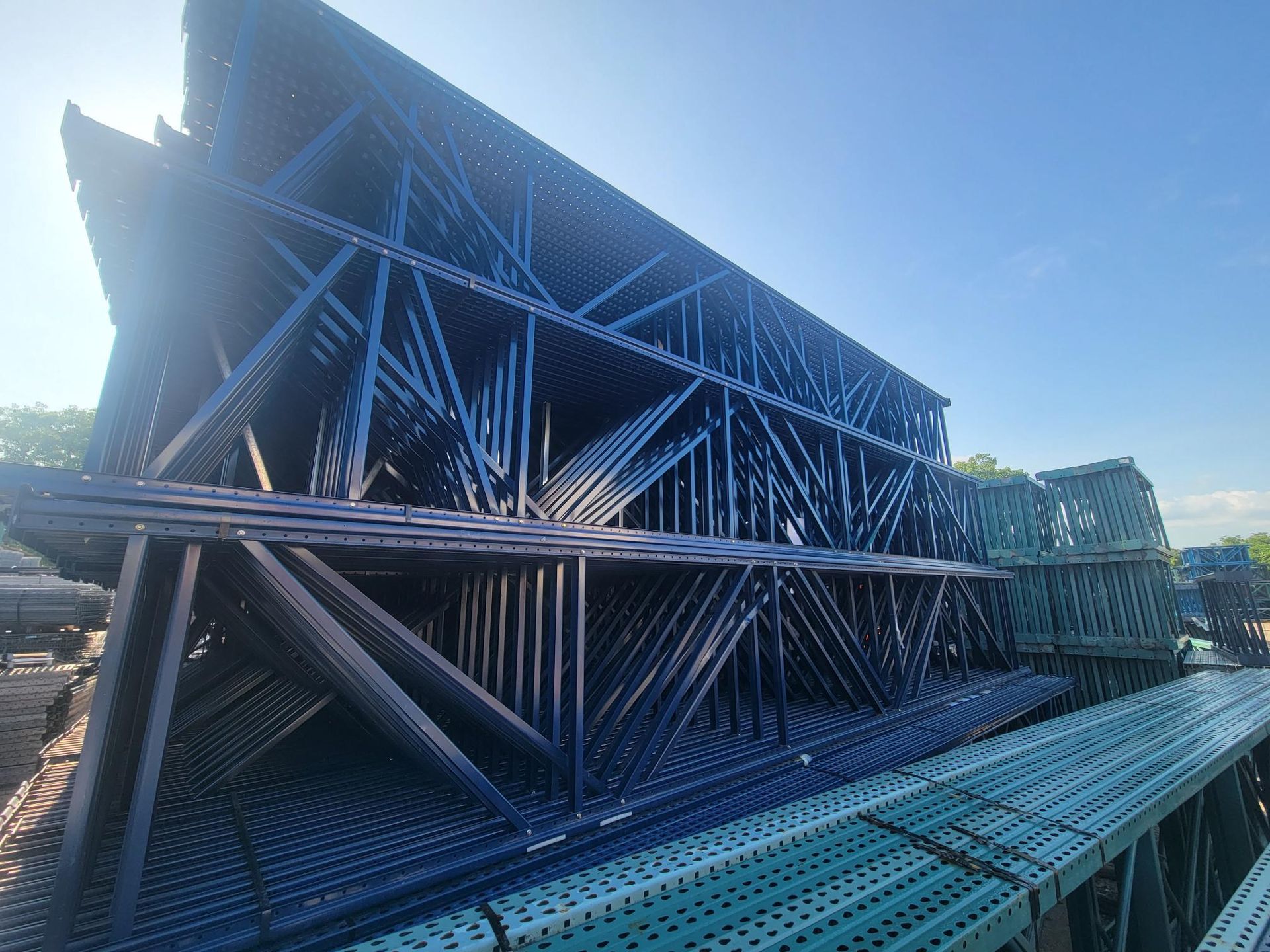A stack of blue metal scaffolding against a blue sky.