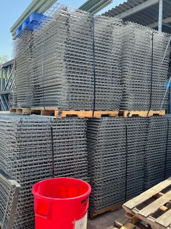 A red trash can is sitting next to a stack of metal crates.