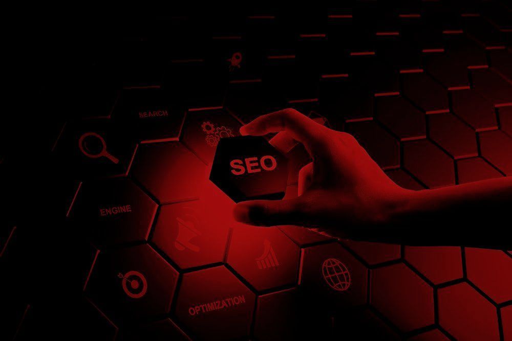 A hand is holding a red hexagon with the word seo on it. A hand is holding a red hexagon with the word seo on it.