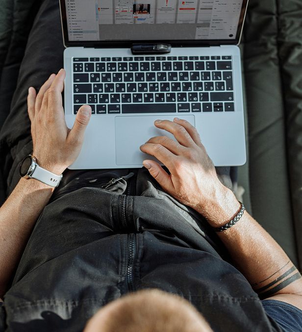 A man is laying on a couch using a laptop computer