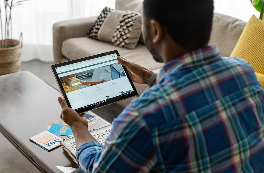 A man is sitting at a table using a tablet computer.