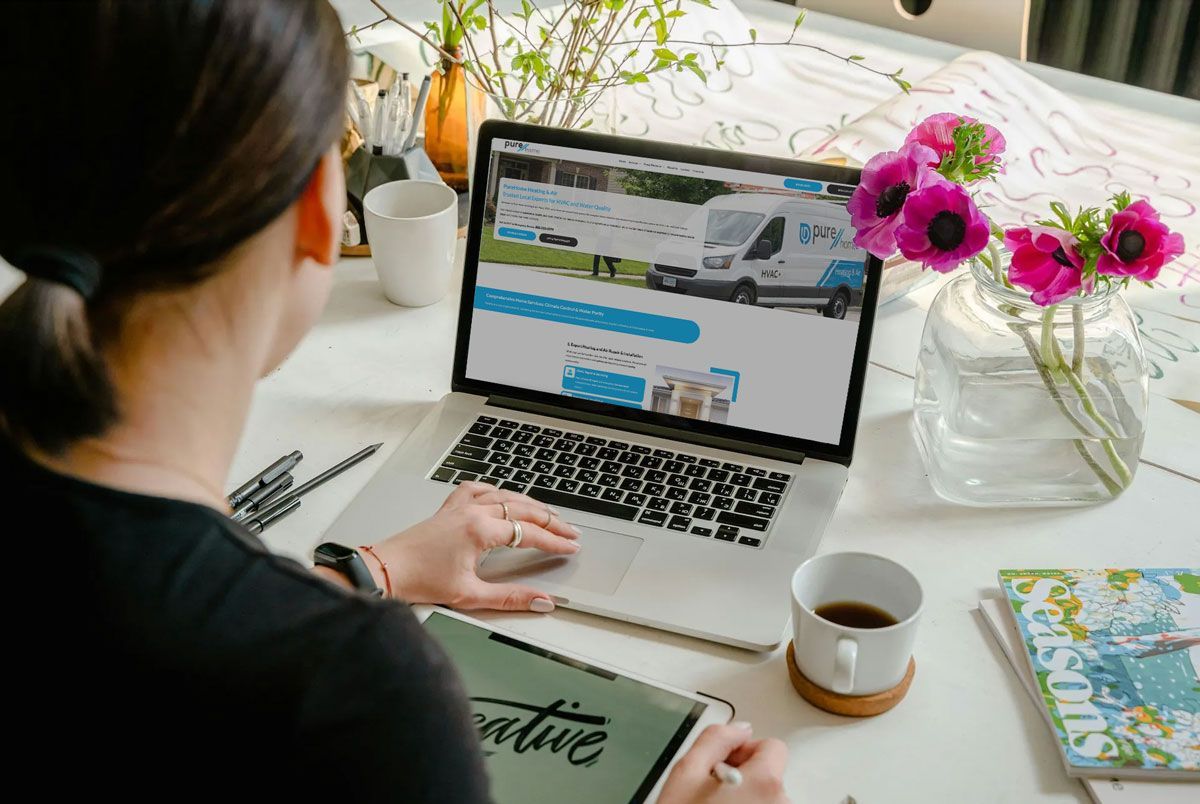 A man is sitting at a desk in front of three computer monitors.