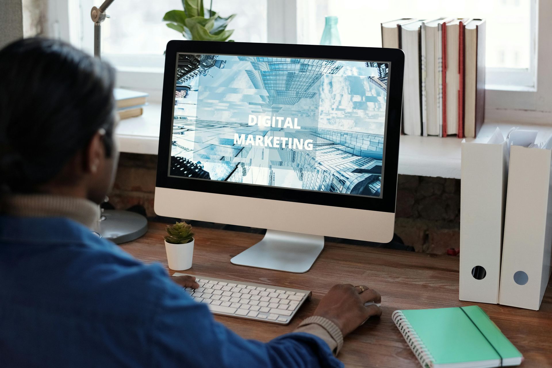A man is sitting at a desk in front of three computer monitors.