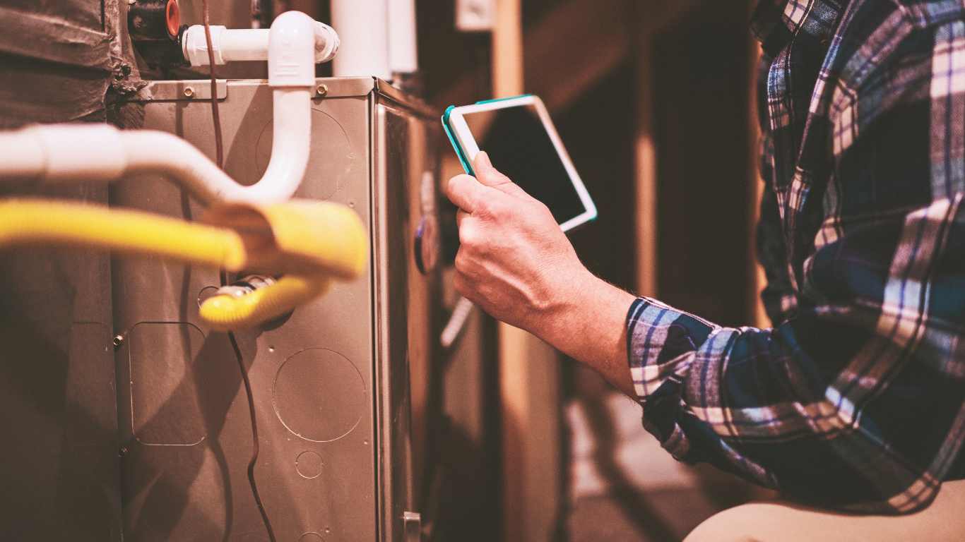 A man is using a remote control to turn on an air conditioner.