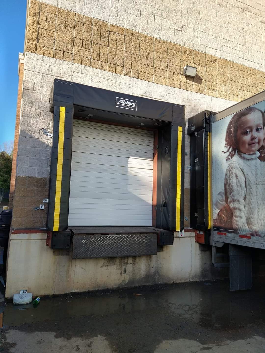 A truck is parked in front of a building with a dock door.