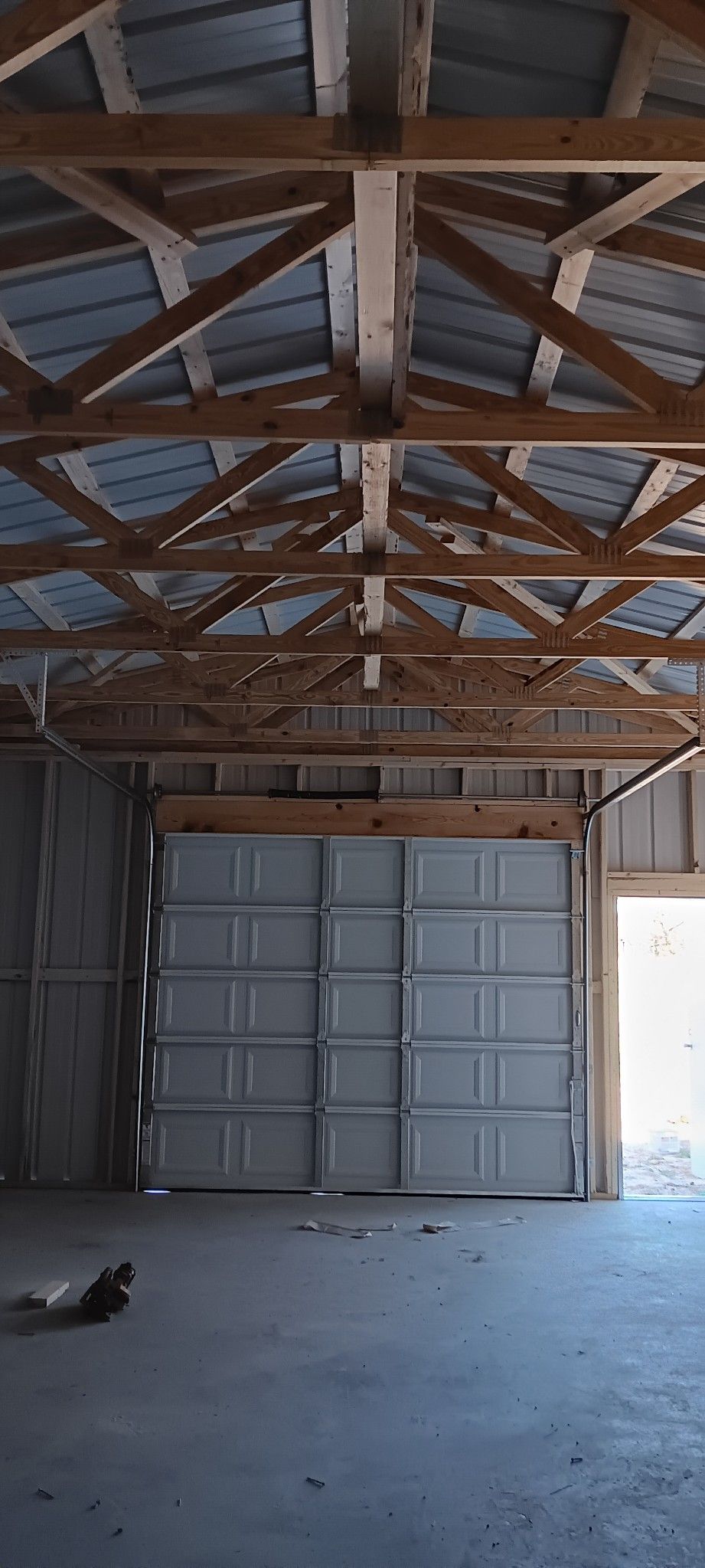 A garage with a large garage door and a wooden roof.