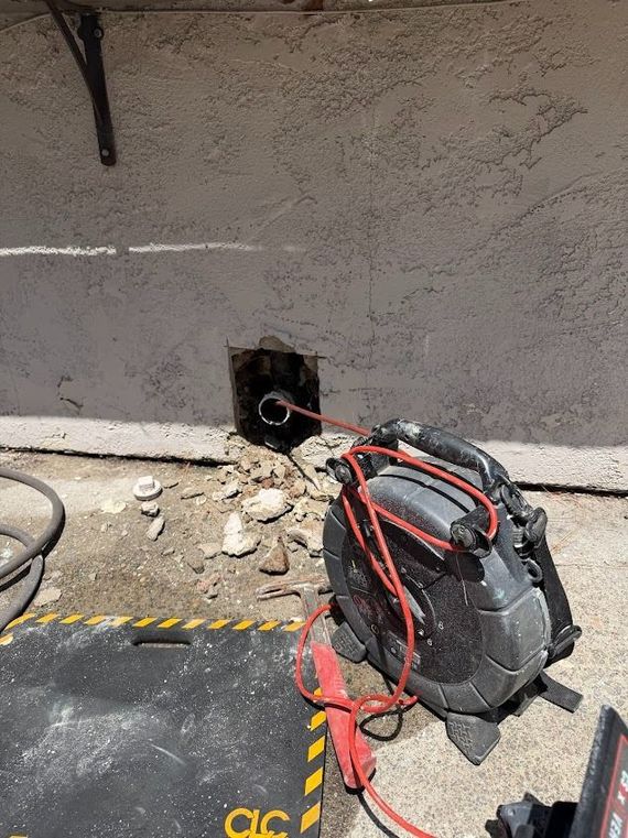 Backpack vacuum and red extension cord beside a wall outlet in a dusty construction area