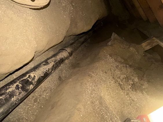 Close-up of a dusty, beige interior space with a black rod or cable running across the floor.