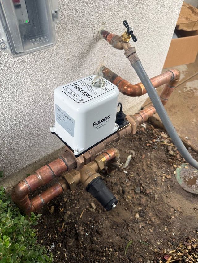 Outdoor gas meter with copper pipes and a shutoff valve beside a house foundation.