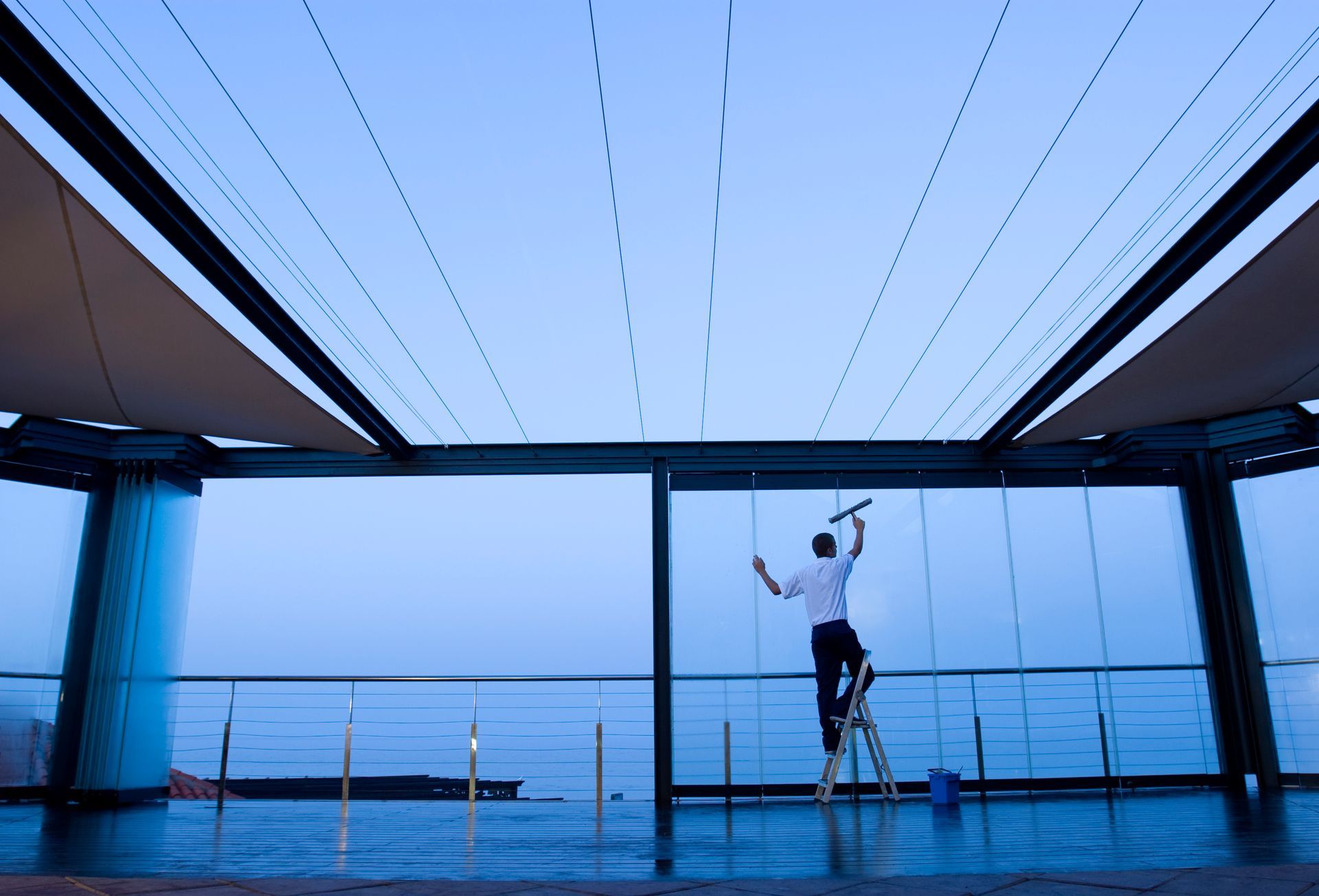 Image of a worker doing early morning cleaning of glass windows.