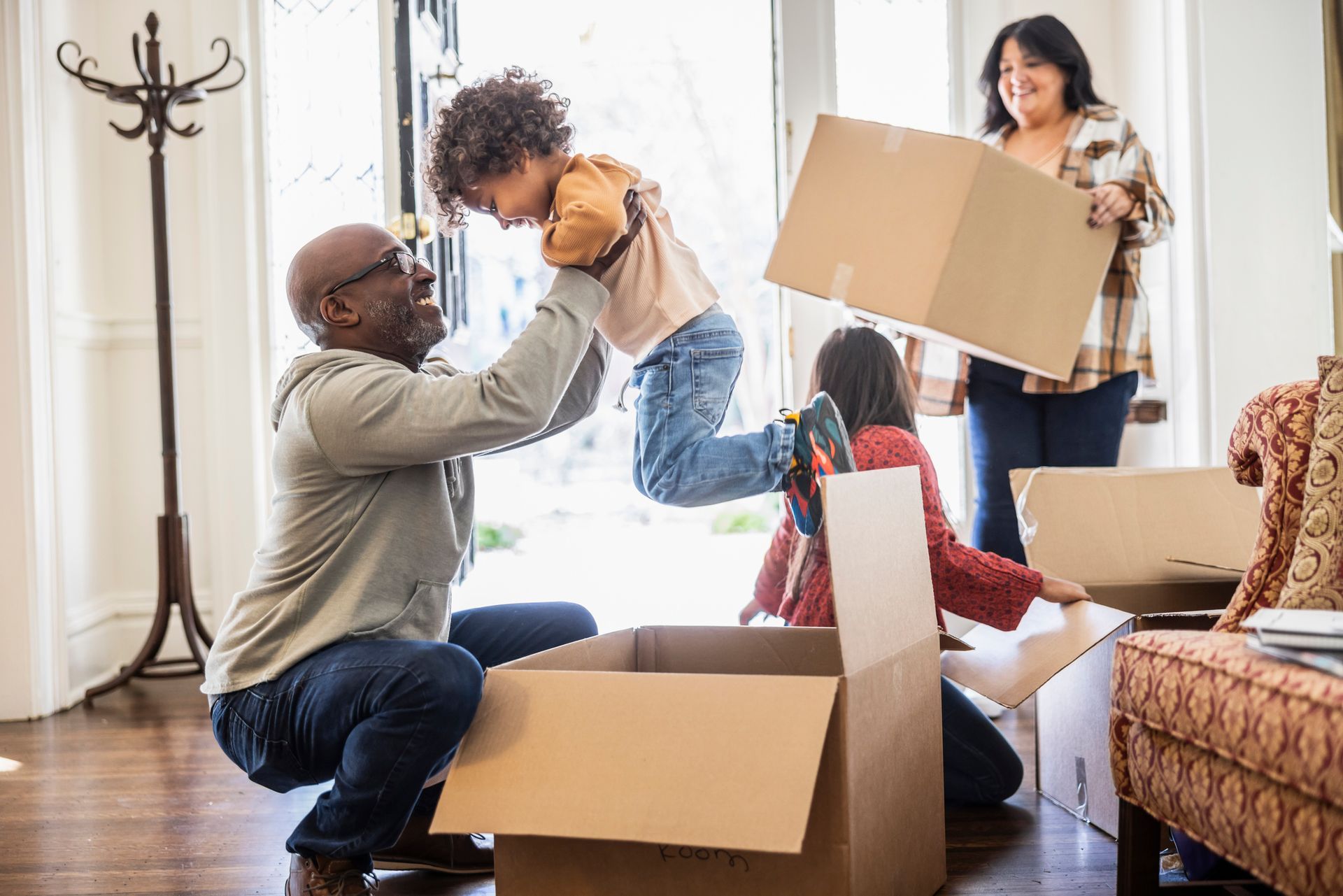 A family is moving into a new home and playing with cardboard boxes.