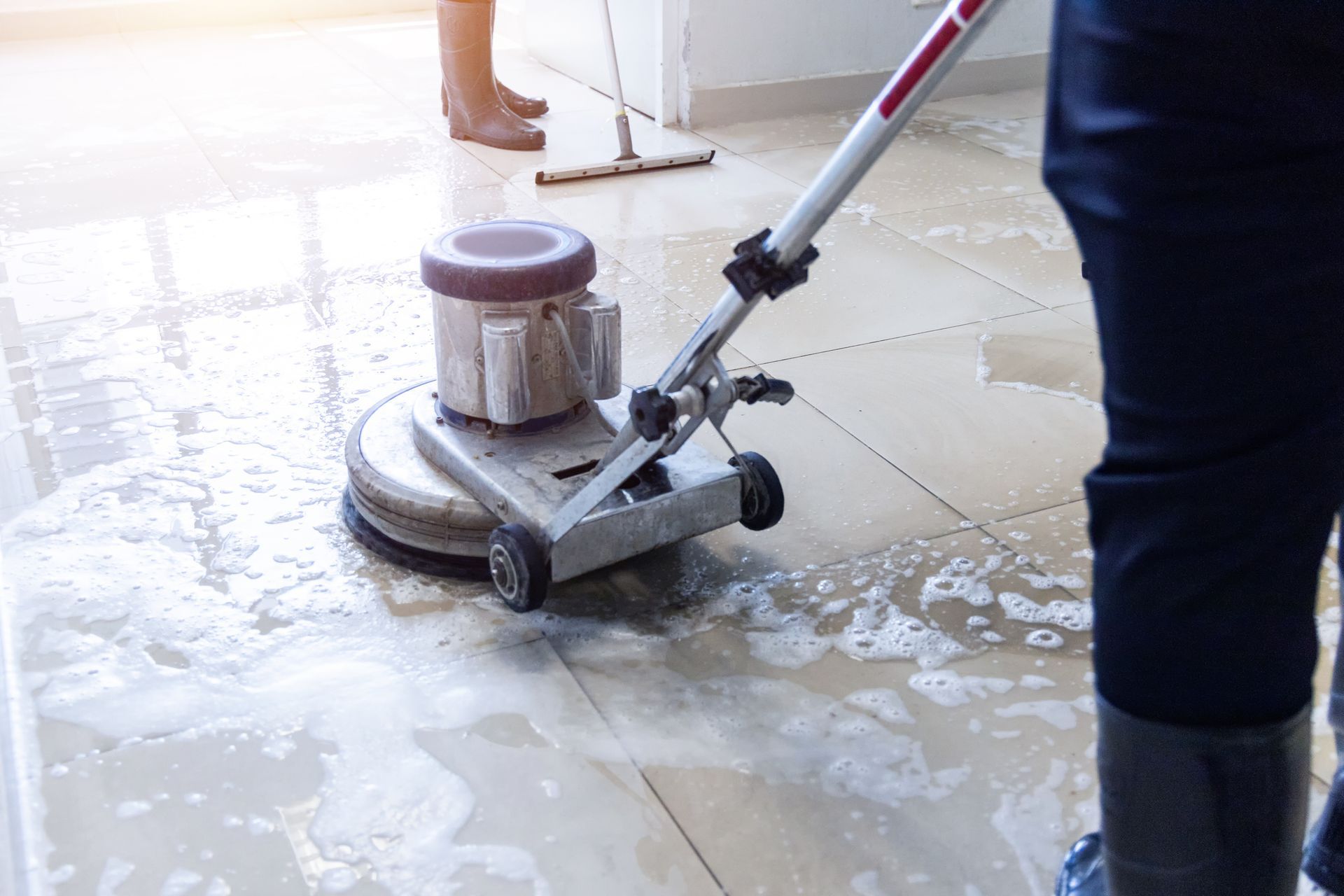 A person is cleaning a tiled floor with a machine.