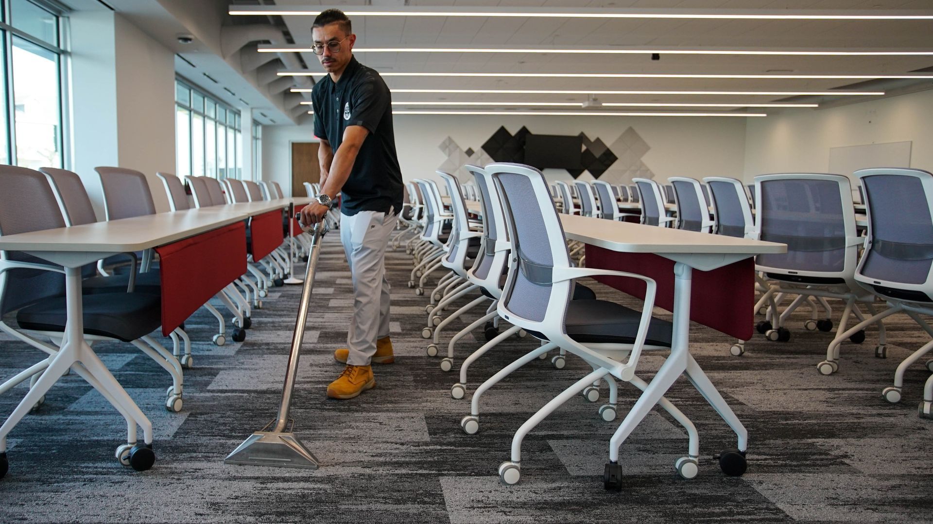 A man is cleaning the floor of a conference room with a mop.