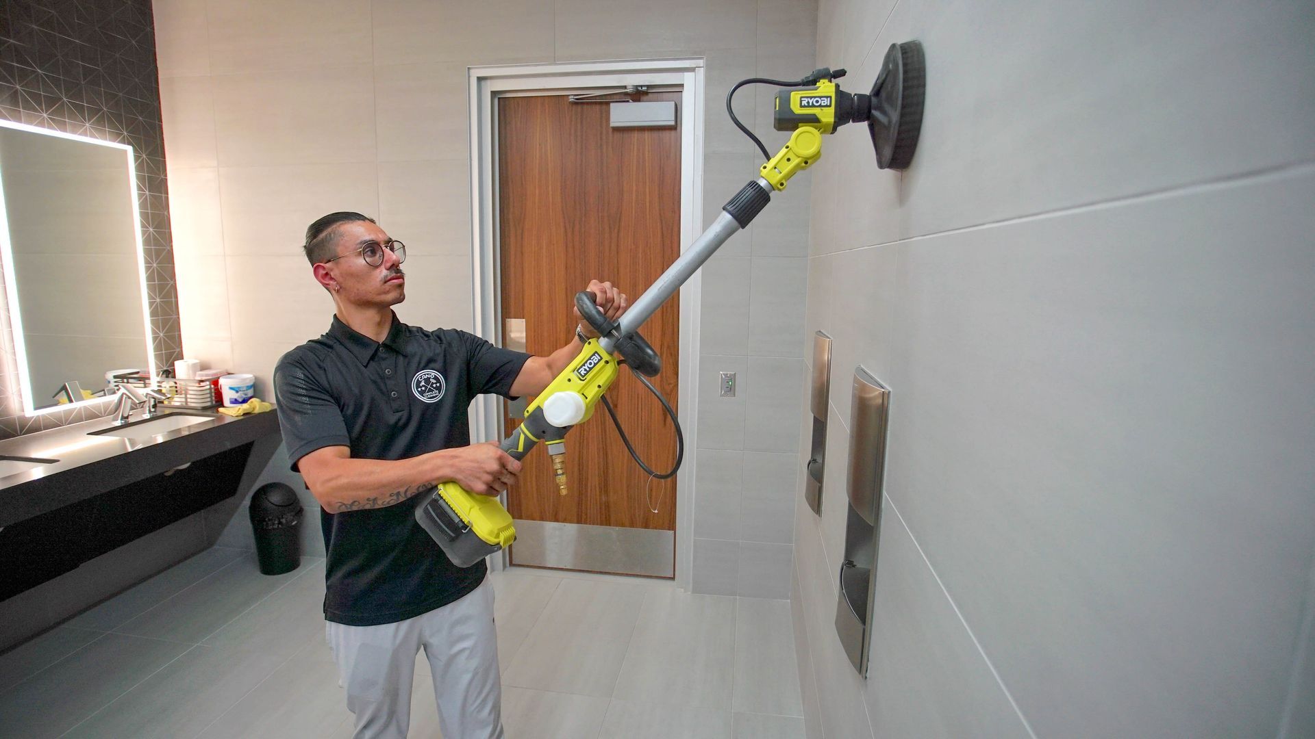 A man is cleaning a wall with a tool in a bathroom.