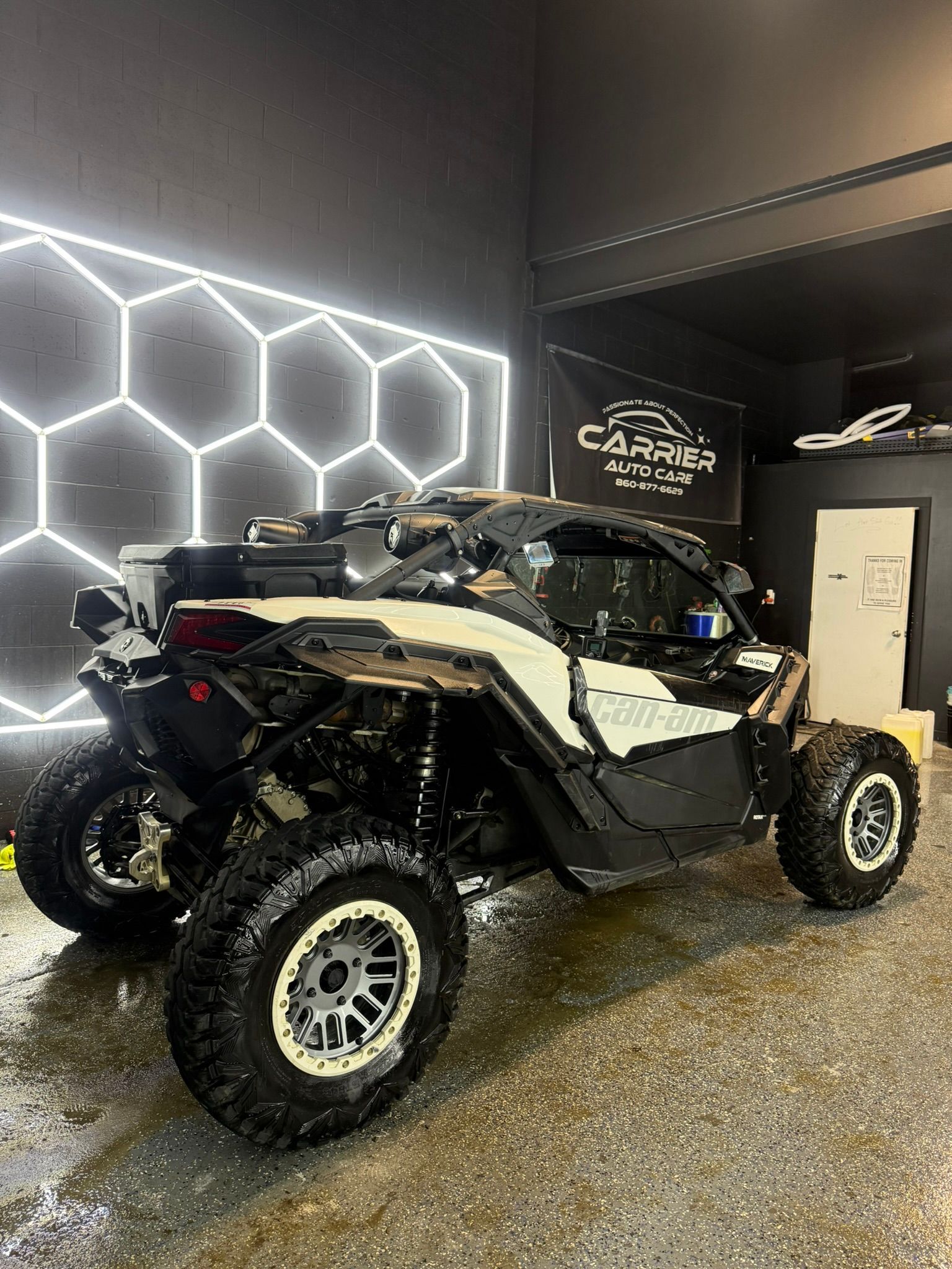 Black and white off-road vehicle parked indoors with hexagonal lights on the wall.