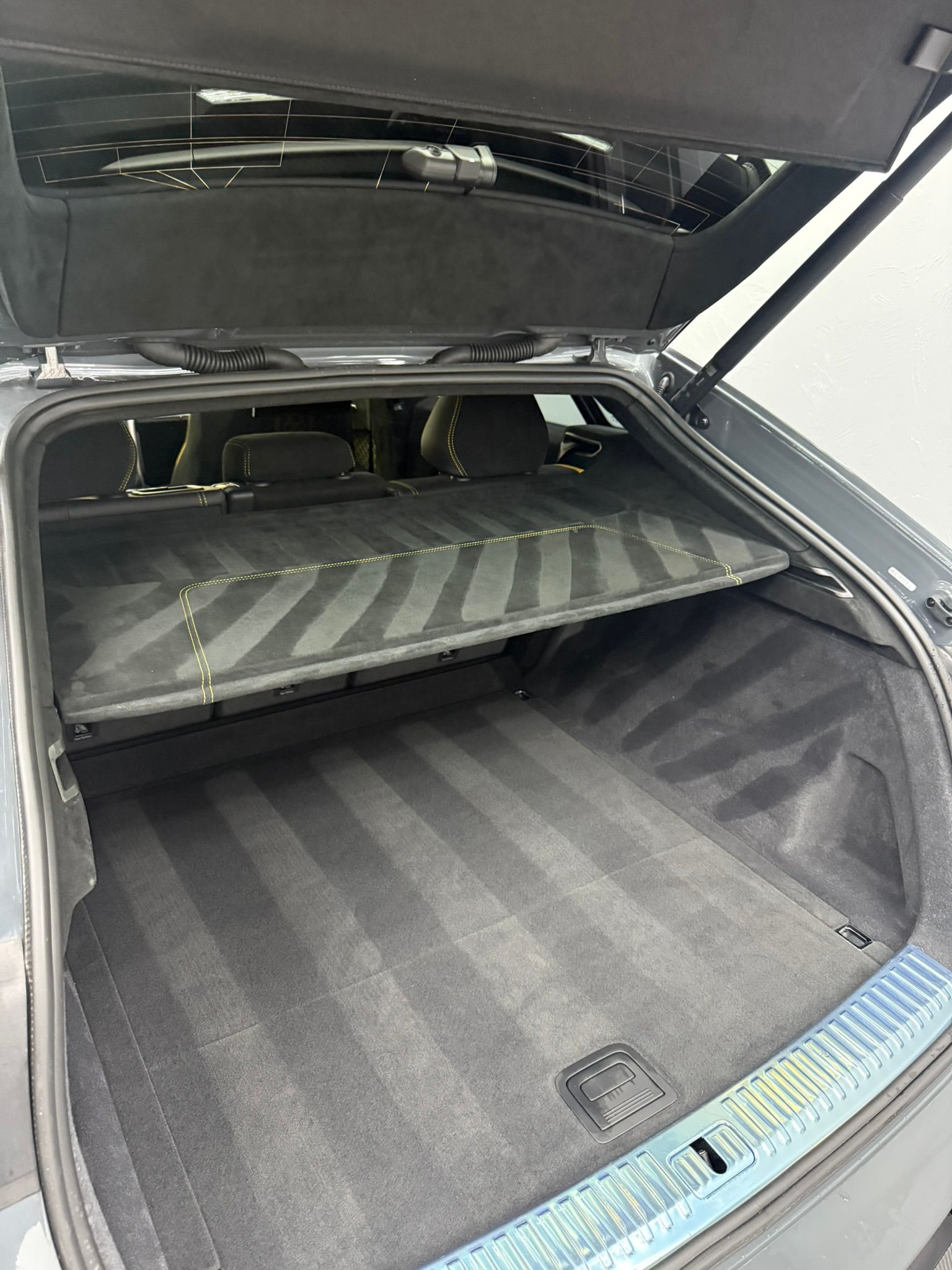 Open car trunk with clean, gray carpet and retractable cover.