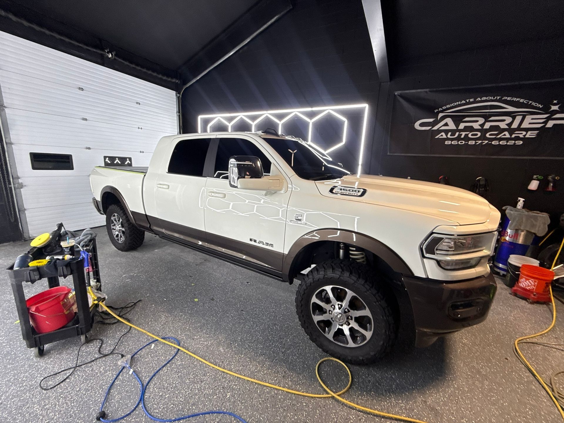 White Ram truck in a car care shop with a black and white Carrier Auto Care sign.