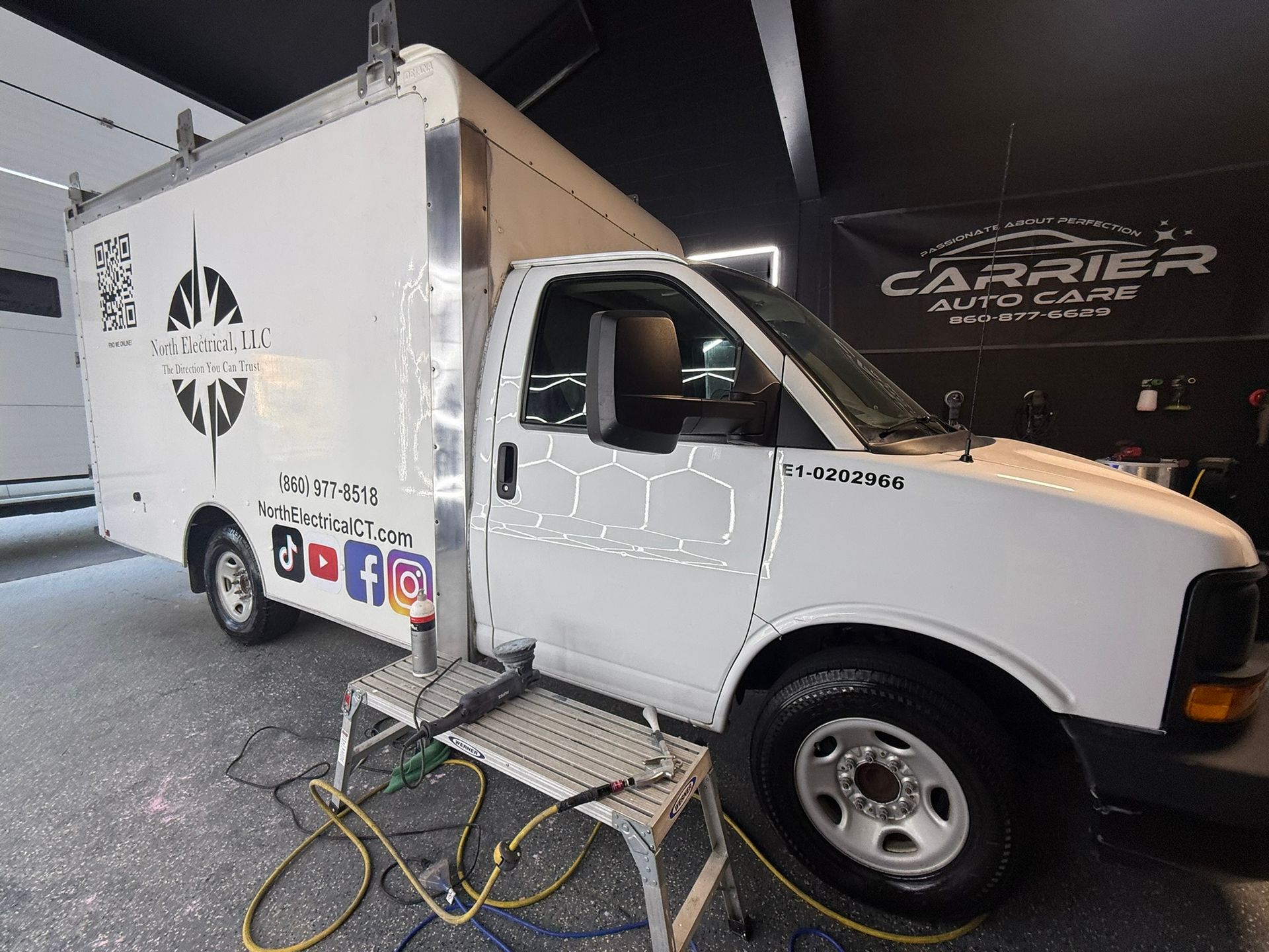 White service truck with a logo parked inside a building with a platform.