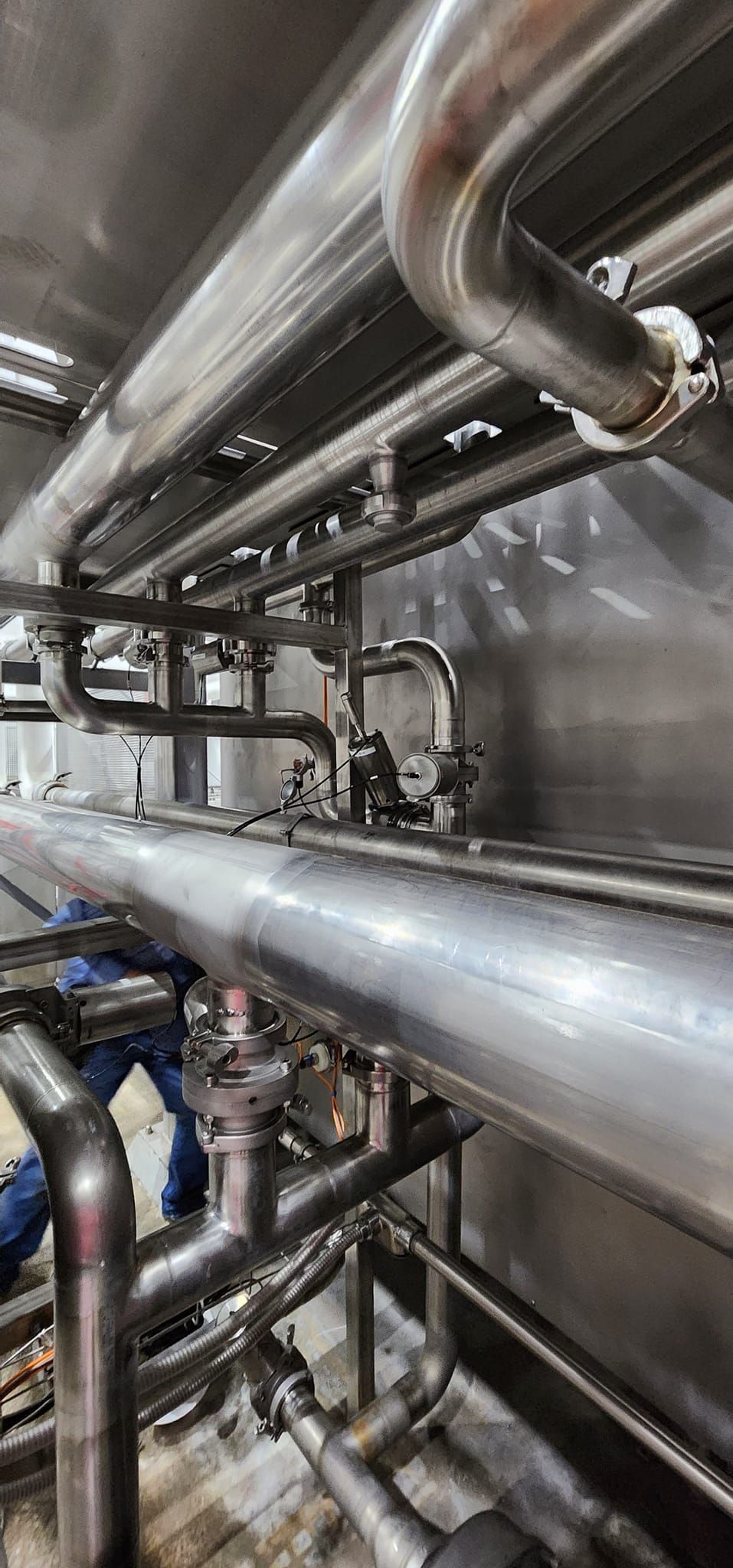 A close up of a row of stainless steel pipes in a factory.