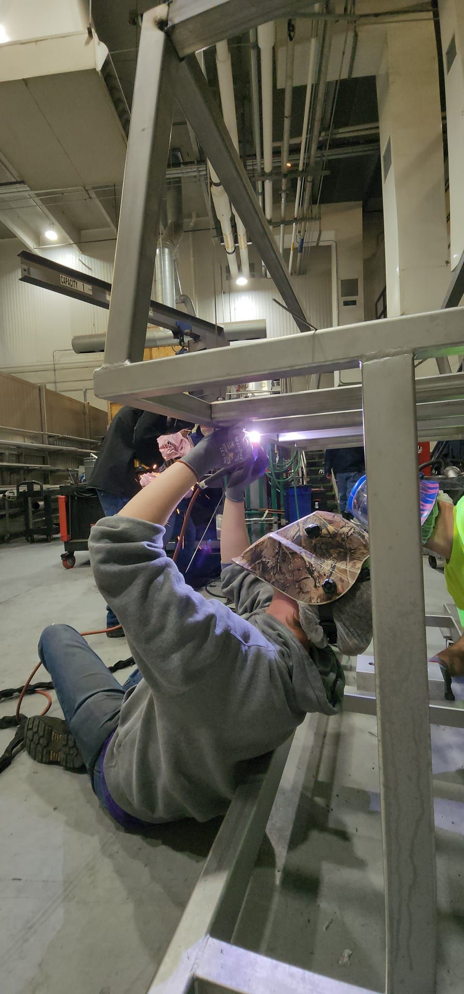 A man is welding a metal structure in a warehouse.