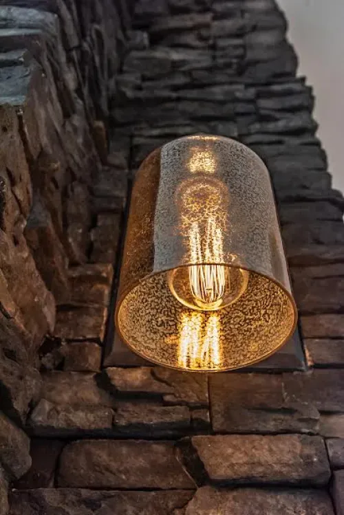A light bulb is hanging from a stone wall.