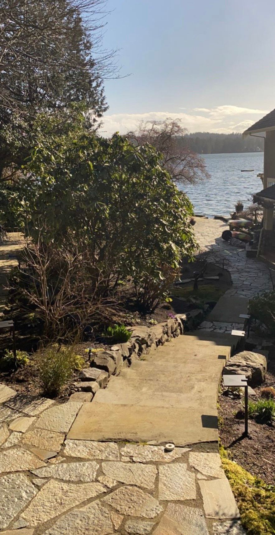 A stone walkway leading up to a house next to a body of water.