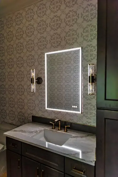 A bathroom with a sink and a mirror with lights on it.